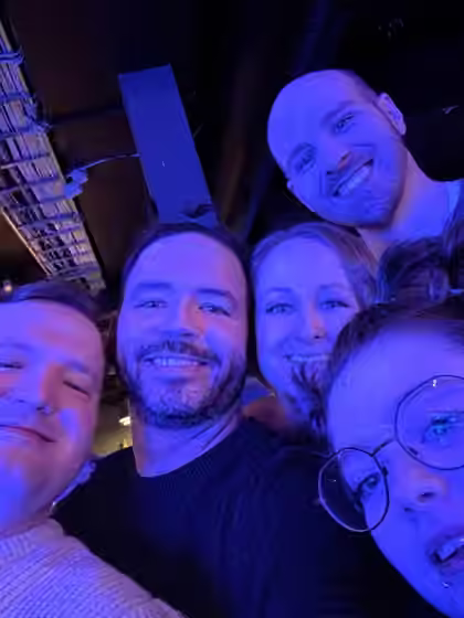 A group of smiling friends at Inside Rock Café under blue lighting